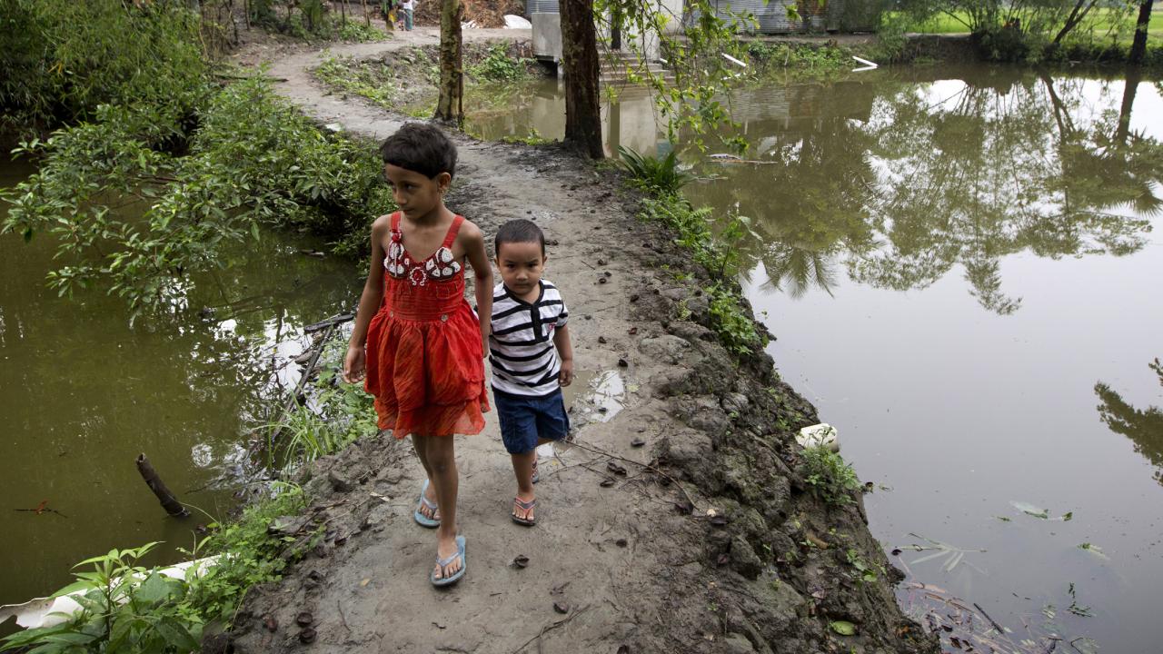 Children in Bangladesh walking on embankment with water on both sides
