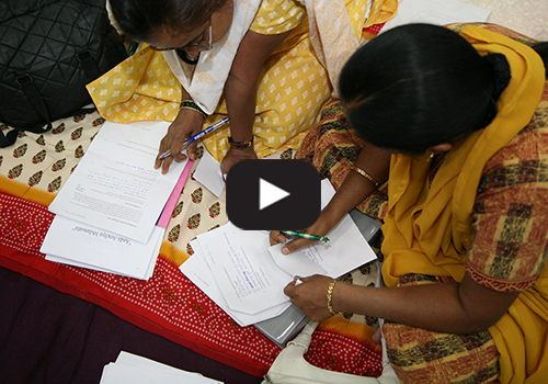 Two women working on papers during the Bhavishya Alliance change lab in 2006