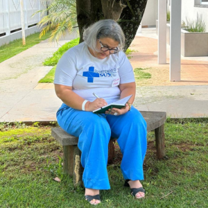 Female healthcare worker, under a tree journaling