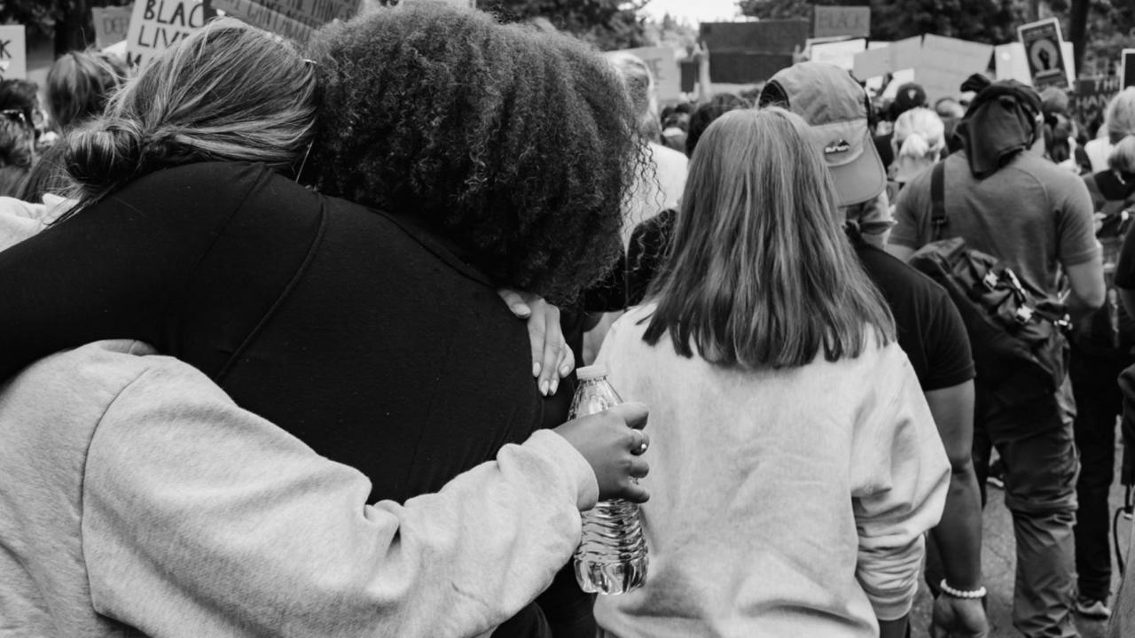 women hugging at racism protest