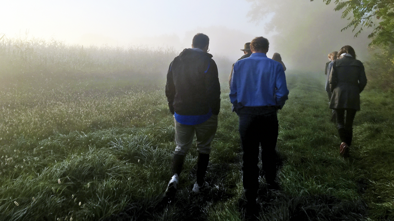 two men talking as they walk through field