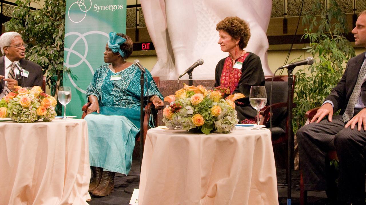 Fazle Hasan Abed on stage speaking with Wangari Maathai, Peggy Dulany, and Jeff Skoll