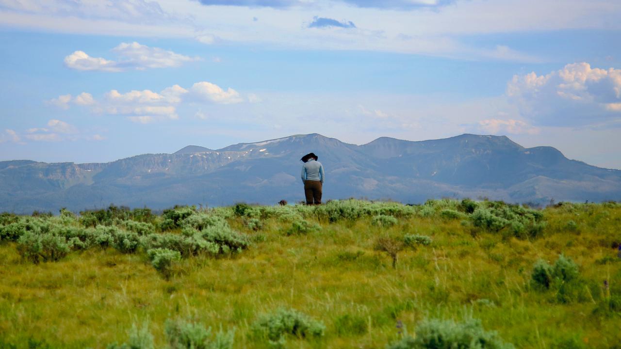 Two people standing outside, facing mountains, in Montana.
