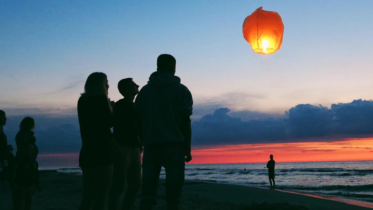 Group on beach watching a lantern